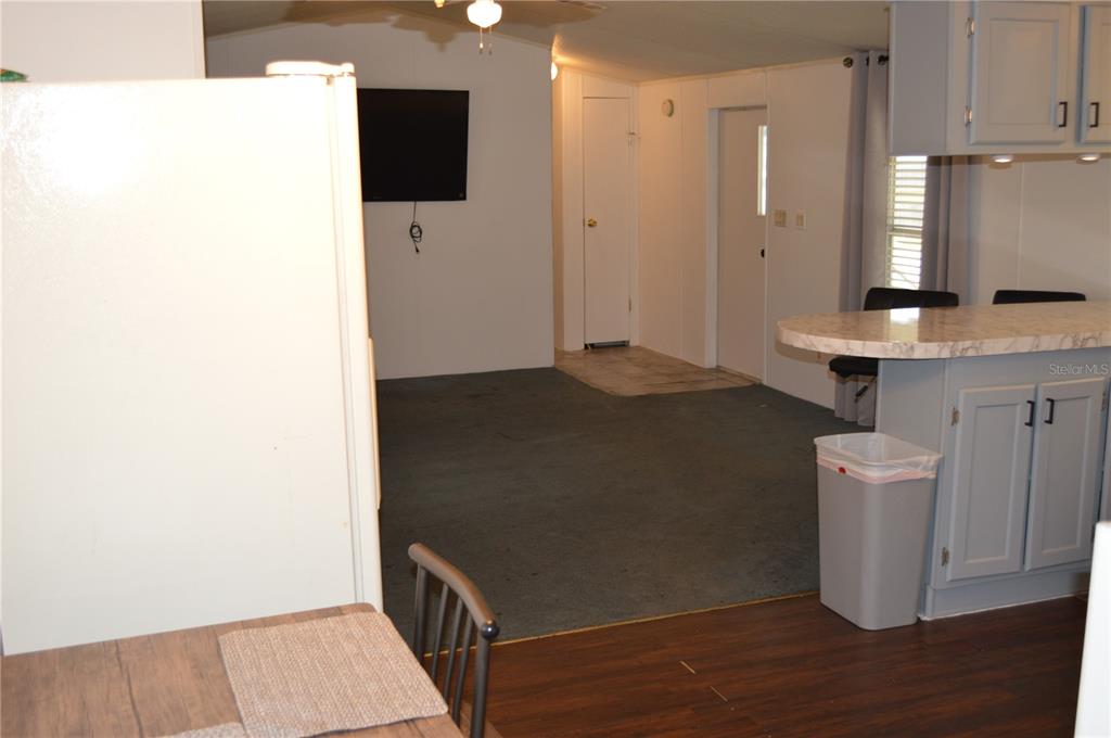 A view from a kitchen looking into a living area with carpet and a television — 349 ELAND DRIVE, NORTH FORT MYERS, FL