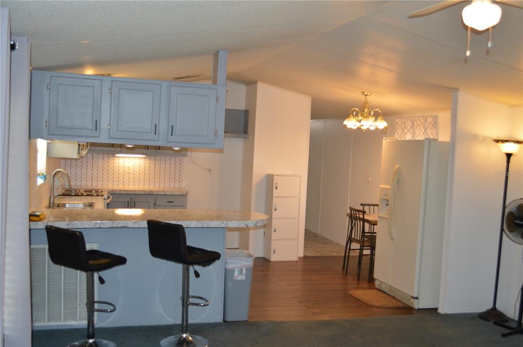 A kitchen features blue cabinets, a marble-look countertop, a breakfast bar, and white appliances — 349 ELAND DRIVE, NORTH FORT MYERS, FL
