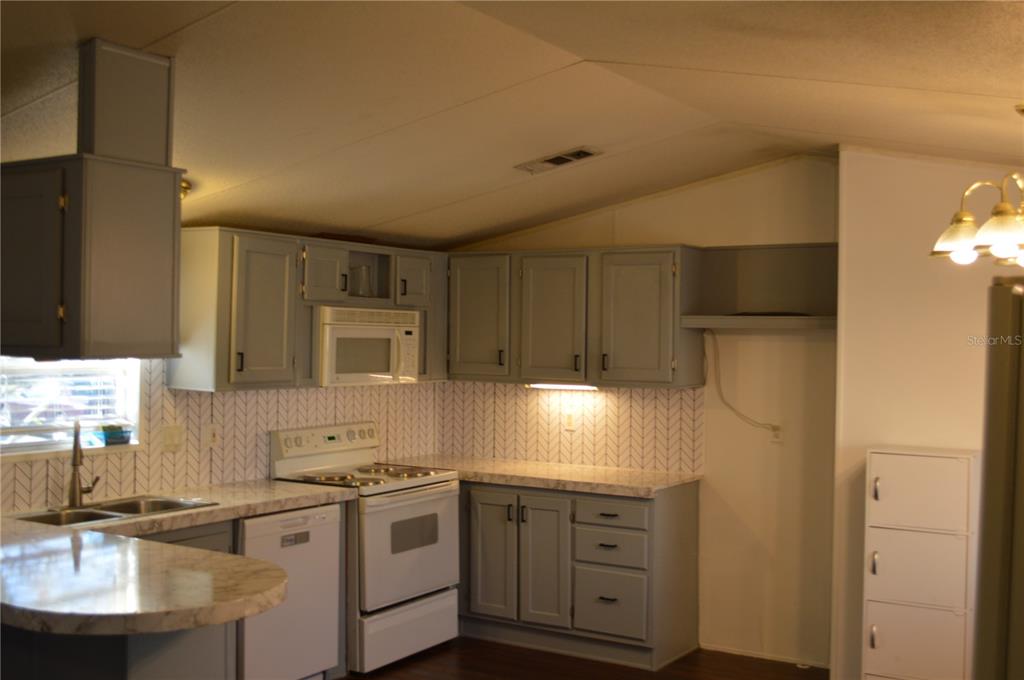 A kitchen with gray cabinets, white appliances, patterned backsplash, and marble-look countertops — 349 ELAND DRIVE, NORTH FORT MYERS, FL
