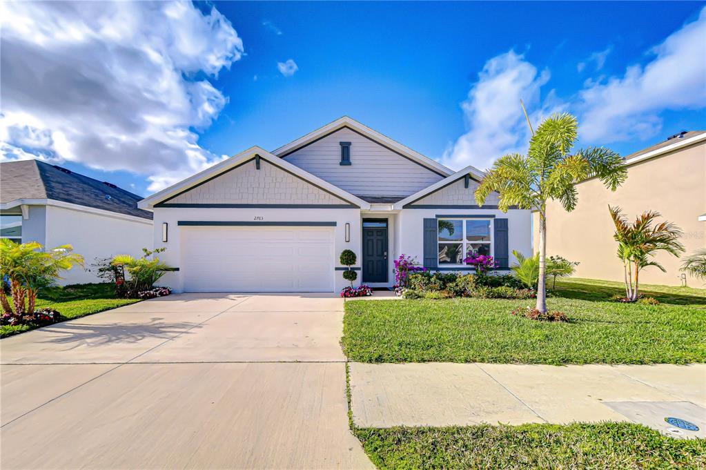 A single-story suburban house with a white garage, gray siding, and a manicured front lawn — 2763 WIDEWATER WAY, ZEPHYRHILLS, FL