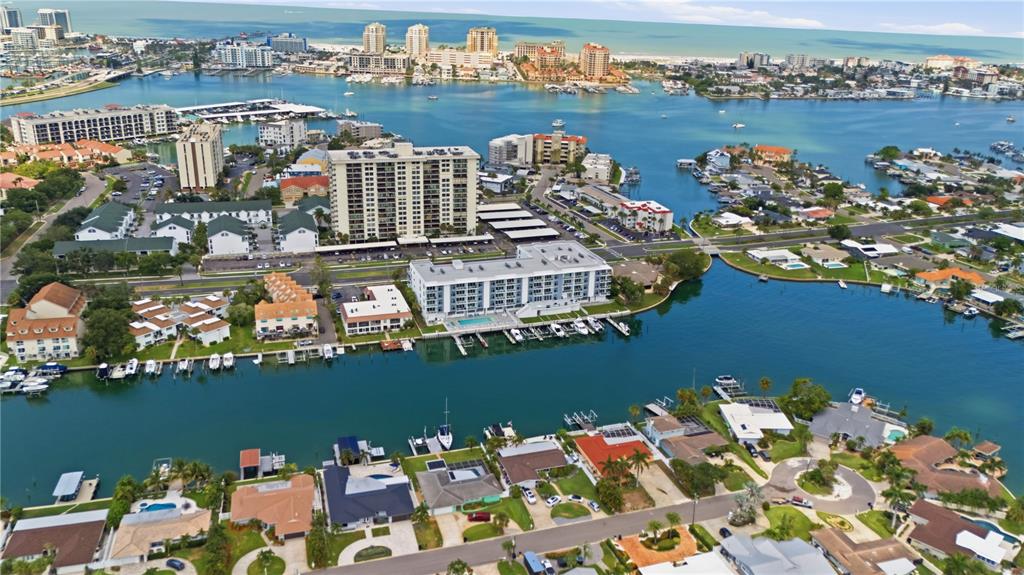 An aerial view shows a waterfront residential area with multi-story apartment buildings and houses — 415 ISLAND WAY UNIT 204, CLEARWATER, FL