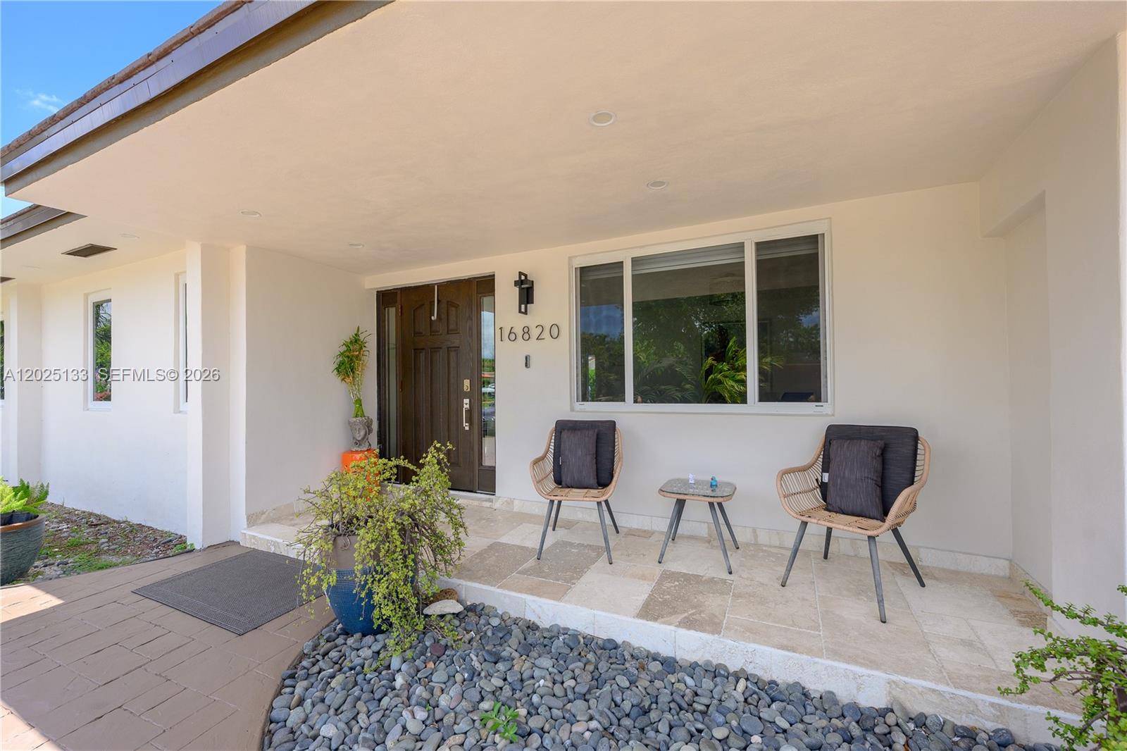 A covered front porch features a tiled floor, two wicker chairs, and a small table — 16820 NW 74th Ave, Hialeah FL 33015, HIALEAH, FL