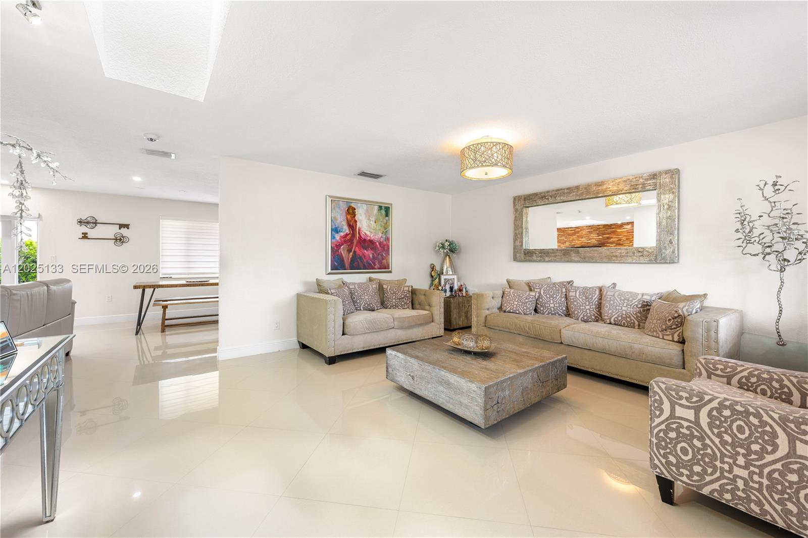 A living room features beige sofas, a wooden coffee table, and a large wall mirror — 16820 NW 74th Ave, Hialeah FL 33015, HIALEAH, FL