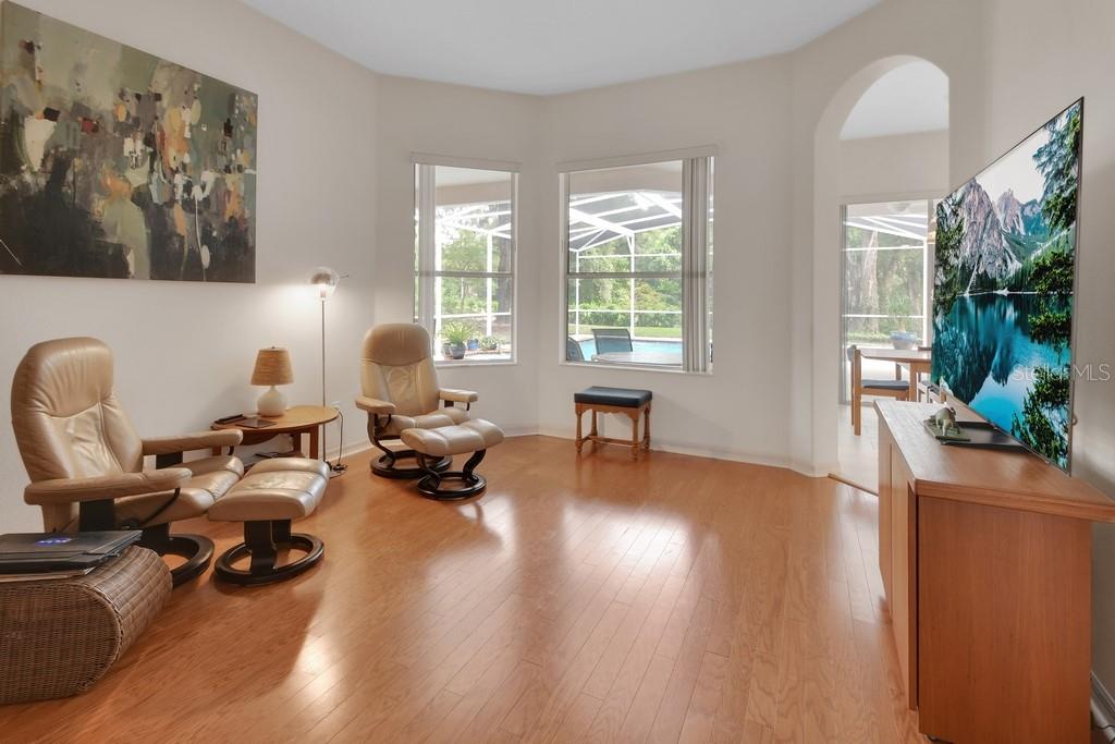 A living room with hardwood floors, two leather recliners, and a large television on a console — 1483 W SILVER HAMMOCK, DELAND, FL