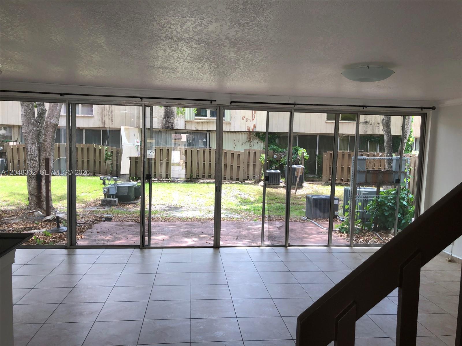 A tiled living room features a large sliding glass door wall overlooking a backyard area — 836 NW 82nd Ave # 3, Plantation FL 33324, PLANTATION, FL