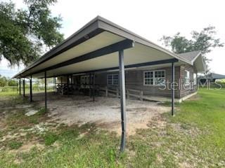 A side view of a house with a large metal carport and a wooden exterior — 10736 US HIGHWAY 301, DADE CITY, FL