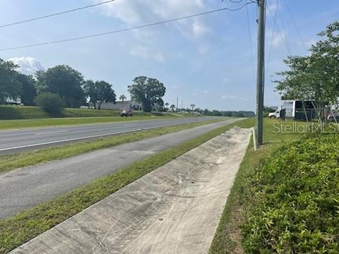 A paved drainage ditch runs alongside a road with a grassy shoulder and distant trees — 10736 US HIGHWAY 301, DADE CITY, FL