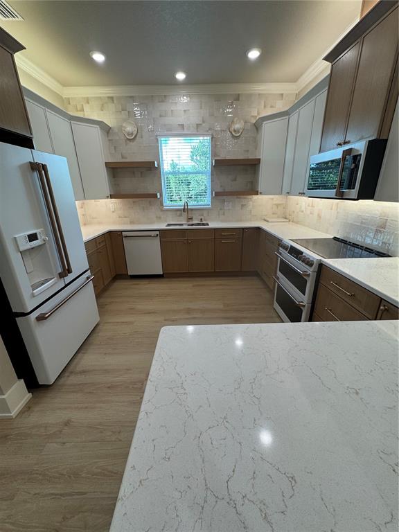 A kitchen features white and wood-toned cabinetry, quartz countertops, and stainless steel appliances — 8308 GIBSON OAKS DRIVE, LAKELAND, FL