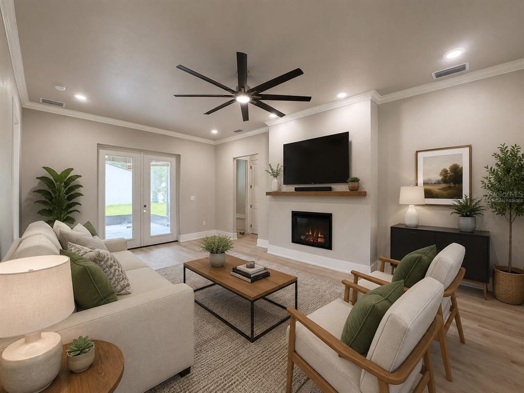 A living room features a fireplace, wall-mounted television, ceiling fan, and neutral furniture — 8308 GIBSON OAKS DRIVE, LAKELAND, FL