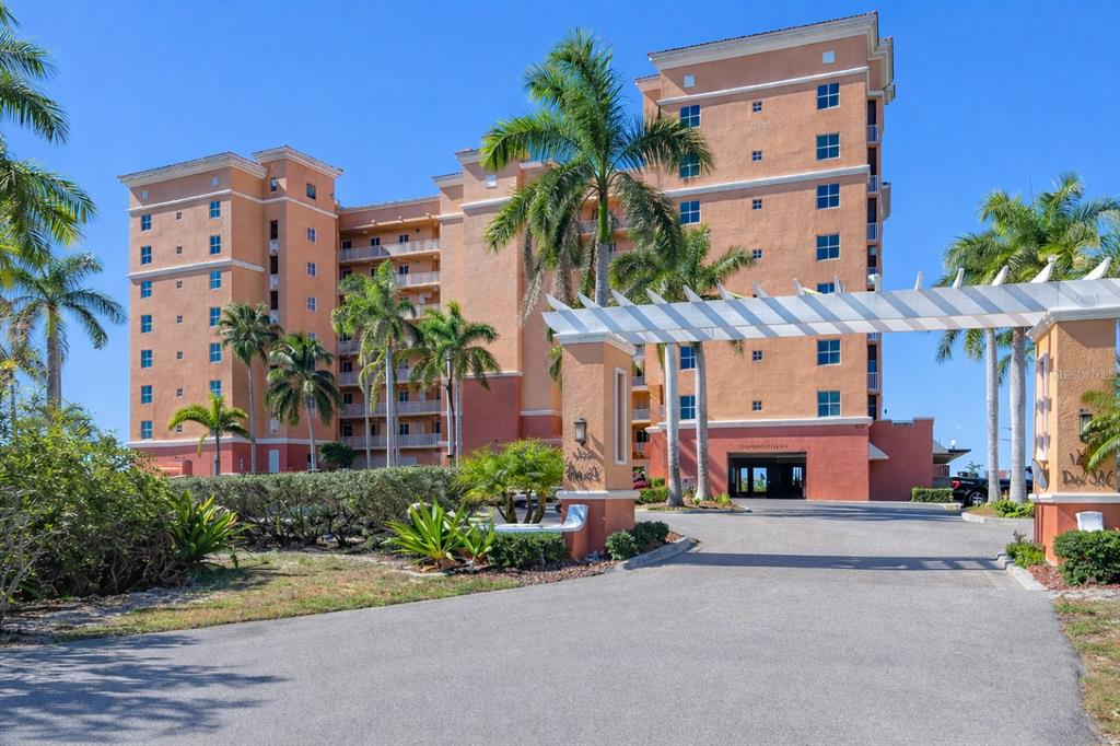 A multi-story tan apartment building with palm trees and a white pergola entrance — 3191 MATECUMBE KEY ROAD UNIT 307, PUNTA GORDA, FL