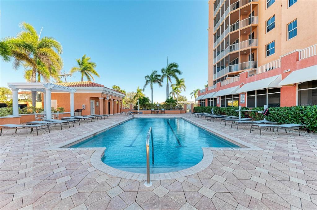 An outdoor swimming pool surrounded by a paved deck, lounge chairs, and palm trees — 3191 MATECUMBE KEY ROAD UNIT 307, PUNTA GORDA, FL