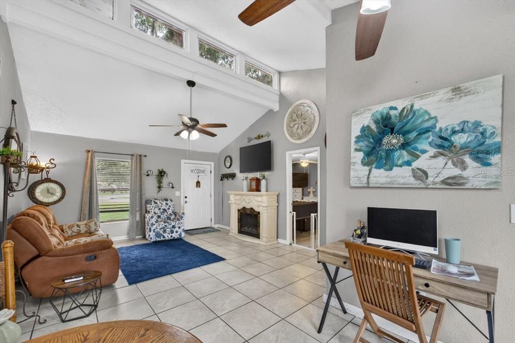 A living room features a vaulted ceiling, tile flooring, a fireplace, and a desk area — 5330 MISTY LAKE DR, MULBERRY, FL