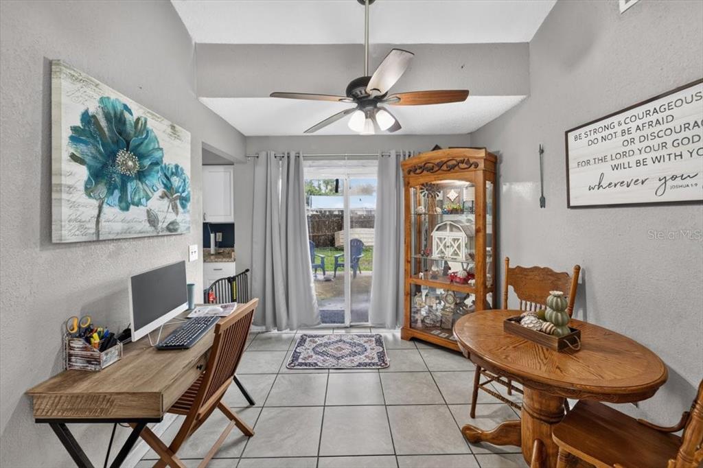 A dining room features a desk, a wooden table, a display cabinet, and sliding glass doors — 5330 MISTY LAKE DR, MULBERRY, FL