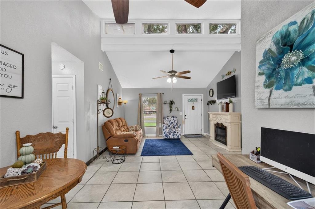 A living room features vaulted ceilings, tile flooring, a fireplace, and a ceiling fan — 5330 MISTY LAKE DR, MULBERRY, FL