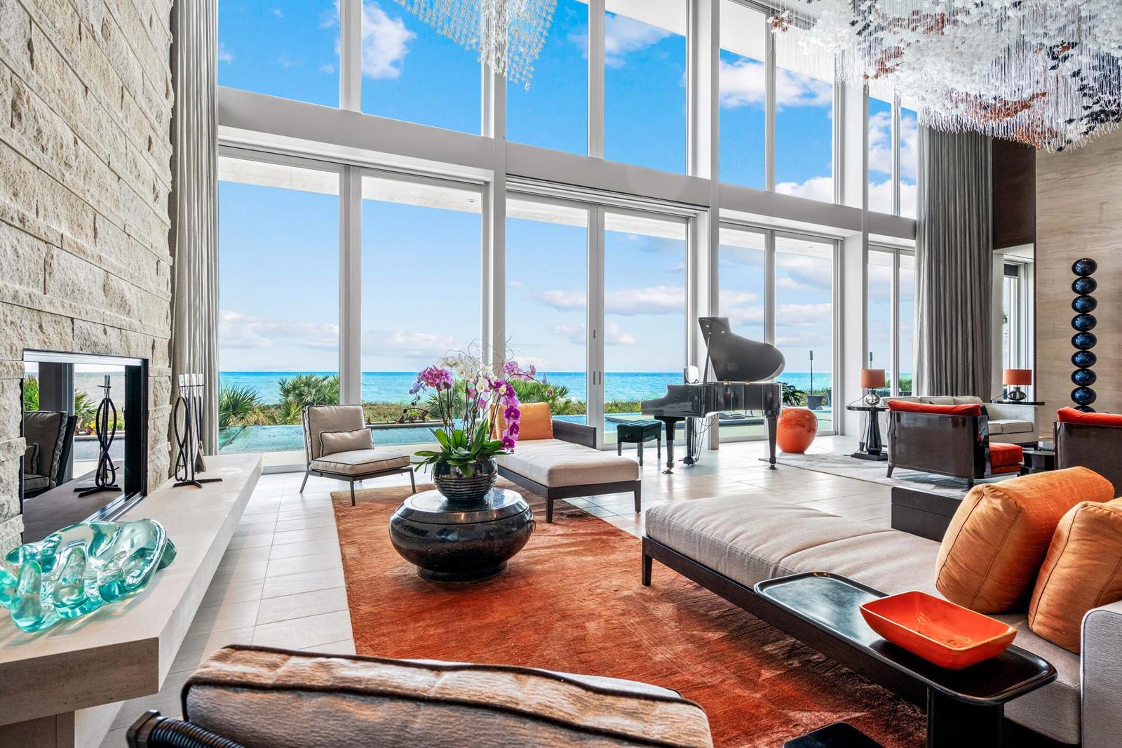 A modern living room with floor-to-ceiling windows, a grand piano, and ocean views — VERO BEACH, FL