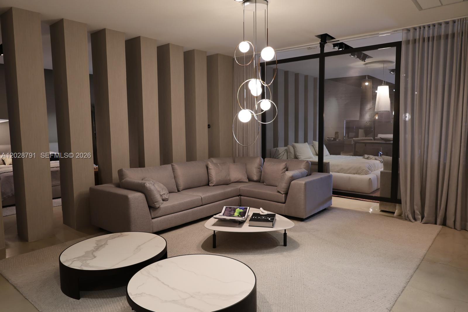A modern living room features a grey sectional sofa, marble-topped coffee tables, and a pendant light — 1810 NE 144th St, North Miami FL 33181, NORTH MIAMI, FL