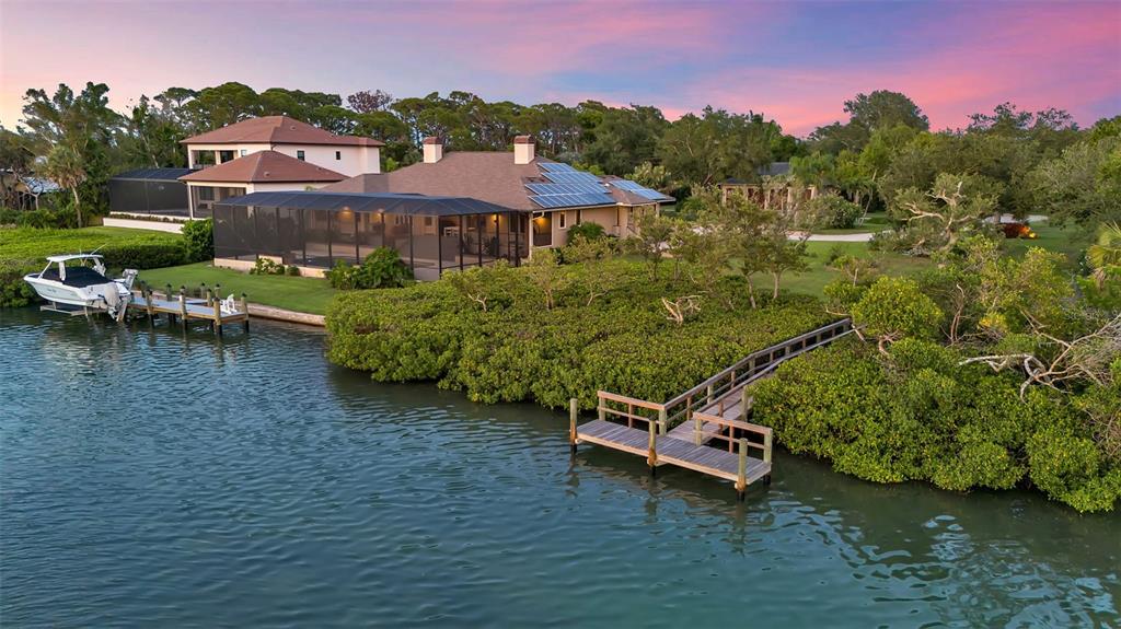 An aerial view shows a waterfront house with a screened pool, dock, and boat lift — 612 LAUREL ROAD W, NOKOMIS, FL
