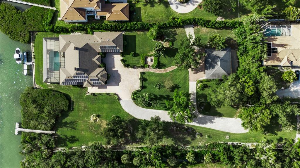 An aerial view shows a large house with solar panels, a pool, and a boat dock — 612 LAUREL ROAD W, NOKOMIS, FL