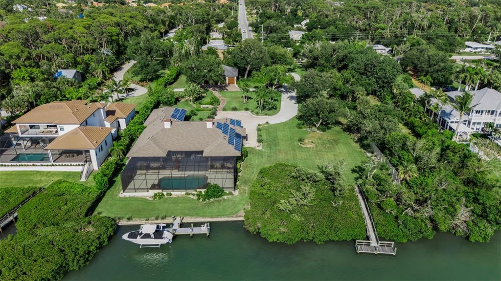An aerial view shows a waterfront house with a pool, solar panels, and a boat dock — 612 LAUREL ROAD W, NOKOMIS, FL