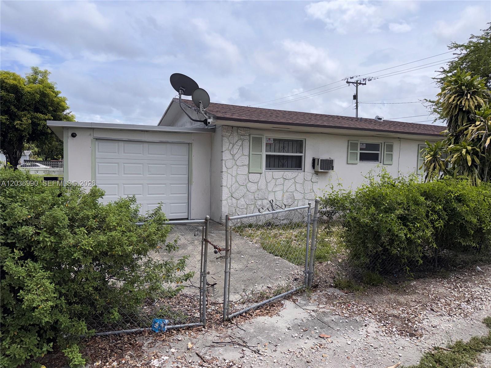 A single-story house with a white garage, stone facade, and a chain-link fence — 7725 NW 14th Ave, Miami FL 33147, MIAMI, FL