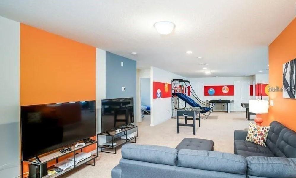 A spacious game room features a television area, a sectional sofa, and various arcade games — 8817 CORCOVADO DRIVE, KISSIMMEE, FL