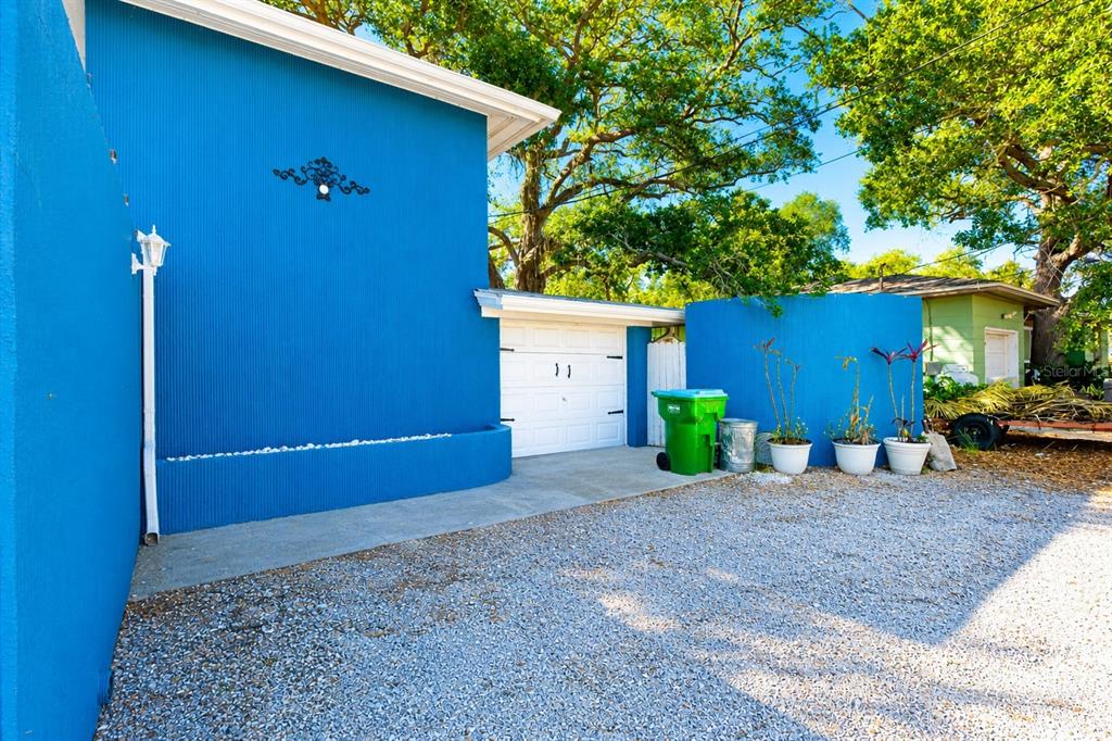 A blue exterior wall, a white garage door, and a gravel driveway are shown — 4720 WELCH CAUSEWAY, ST PETERSBURG, FL