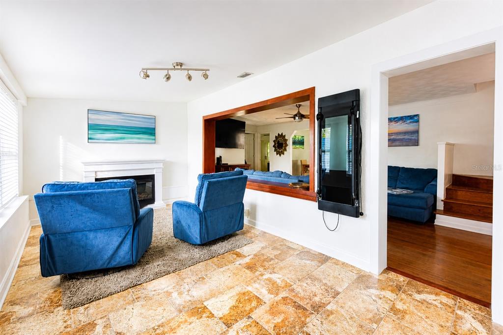 A living room features two blue armchairs, a fireplace, tile flooring, and a pass-through window — 4720 WELCH CAUSEWAY, ST PETERSBURG, FL