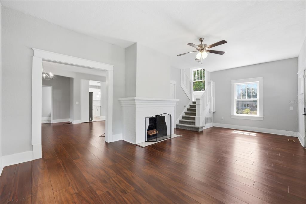 A living room with hardwood floors, a white brick fireplace, and a staircase — 545 E HAINES BOULEVARD, LAKE ALFRED, FL