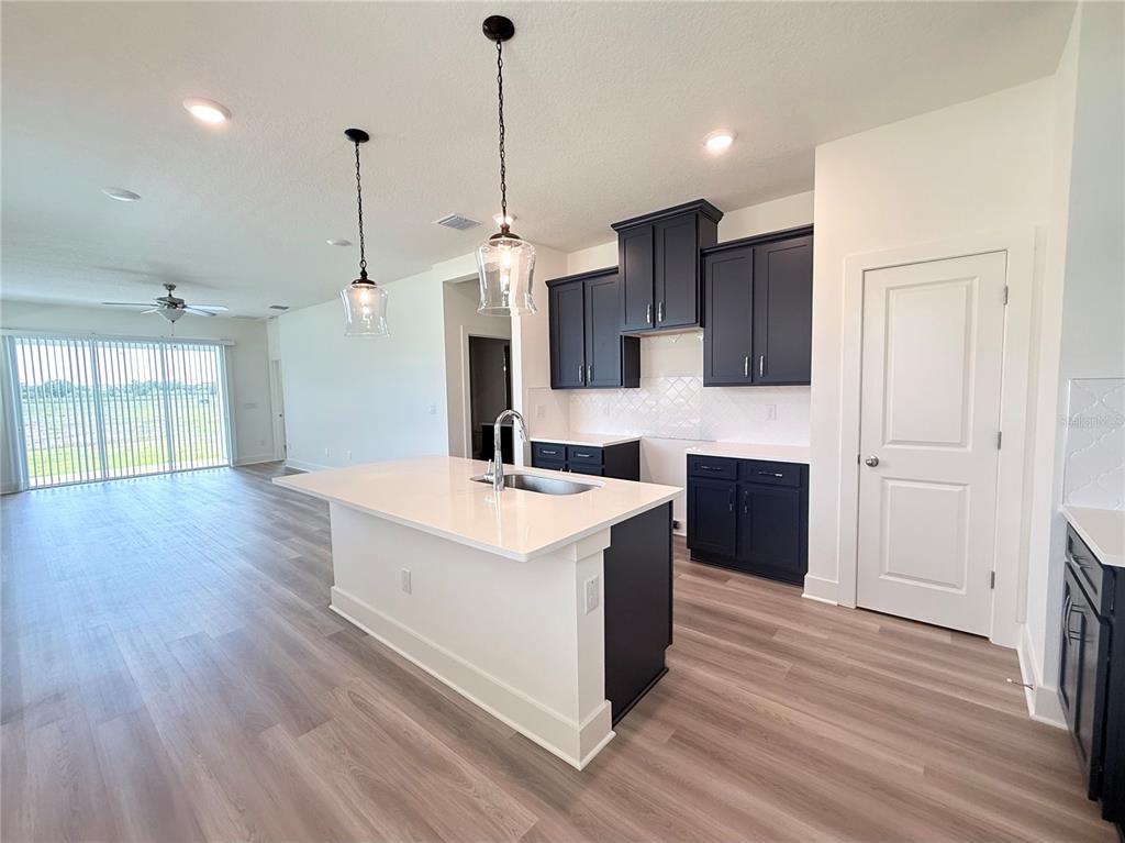 A kitchen features dark blue cabinets, a white quartz island, and light wood-look flooring — 7994 CHANDLER LAKE COURT Lot 16, HUDSON, FL