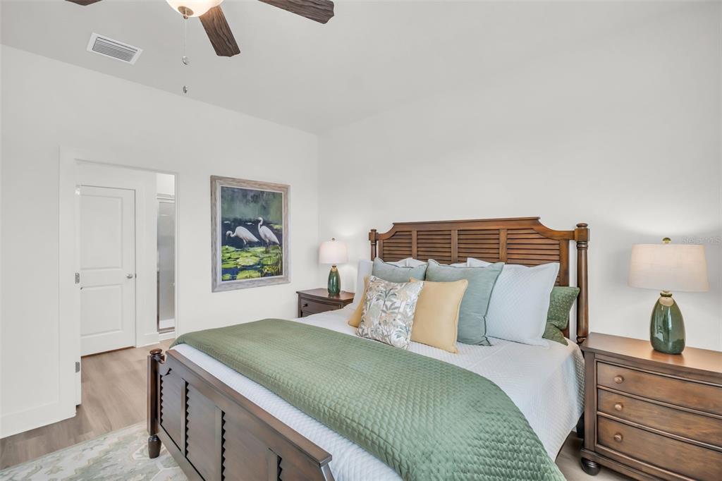 A bedroom features a wooden bed frame, two nightstands with lamps, and a framed painting — 7994 CHANDLER LAKE COURT Lot 16, HUDSON, FL