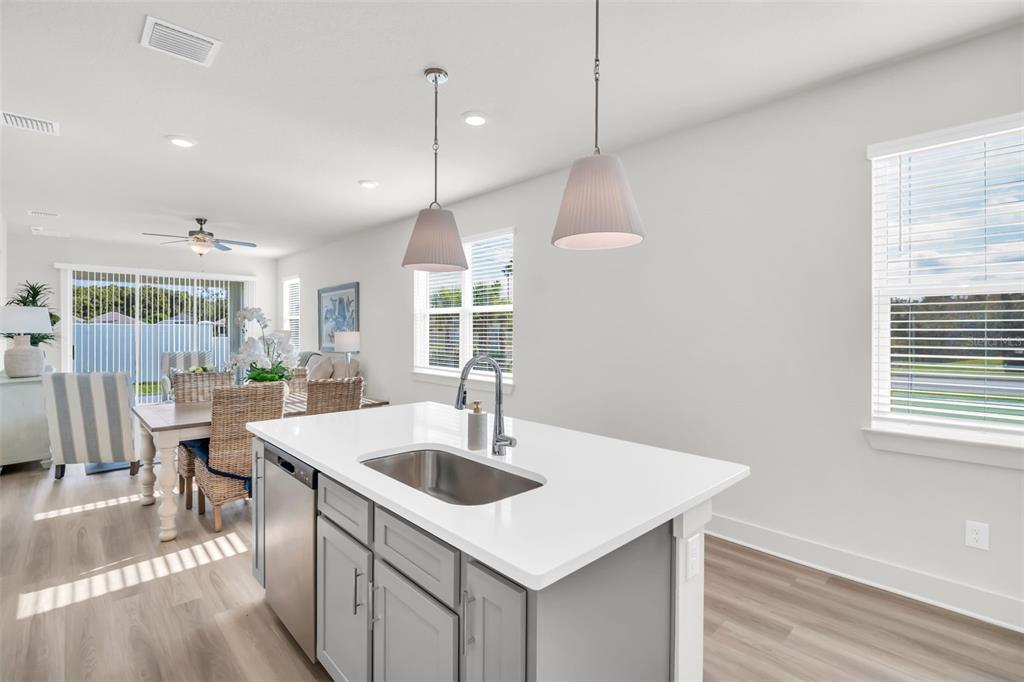 A kitchen island with a stainless steel sink sits before a dining area and windows — 7994 CHANDLER LAKE COURT Lot 16, HUDSON, FL