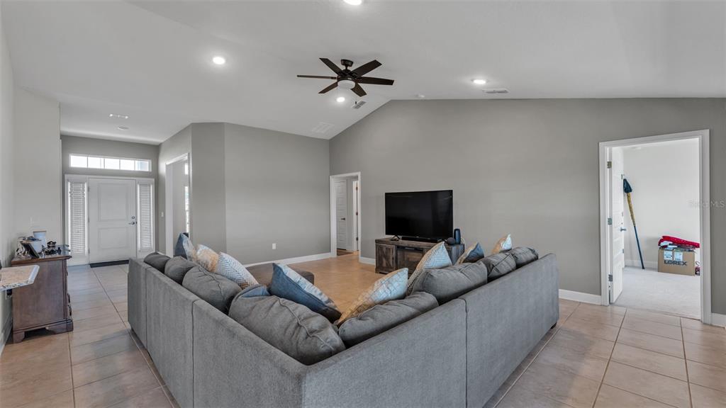 A living room features a large gray sectional sofa, a television, and tile flooring — 4724 BROOKSHIRE COURT, LAKE WALES, FL