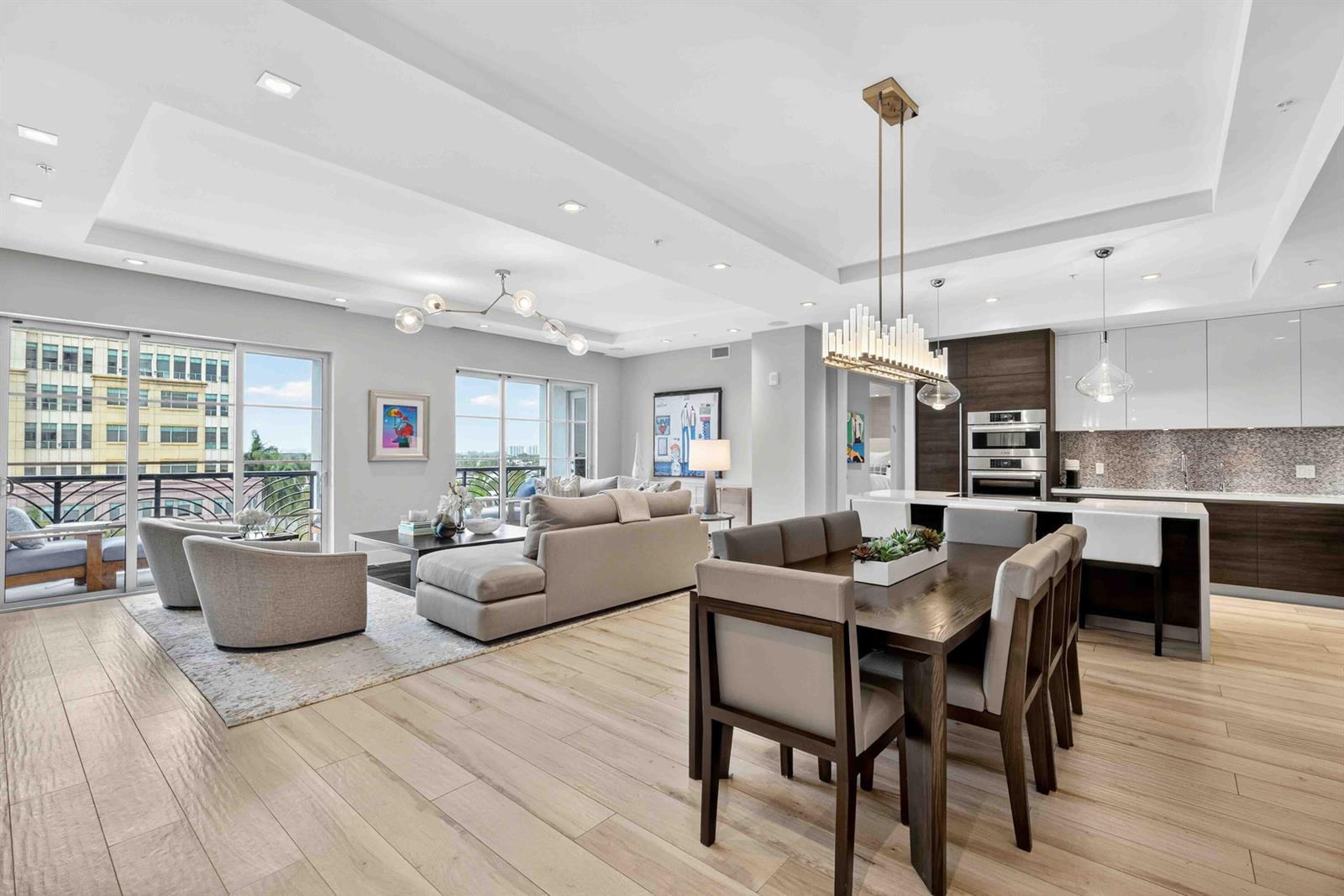 An open-concept living and dining area features light wood floors, modern lighting, and a balcony — 155 E Boca Raton Road # 611, Boca Raton FL 33432, BOCA RATON, FL