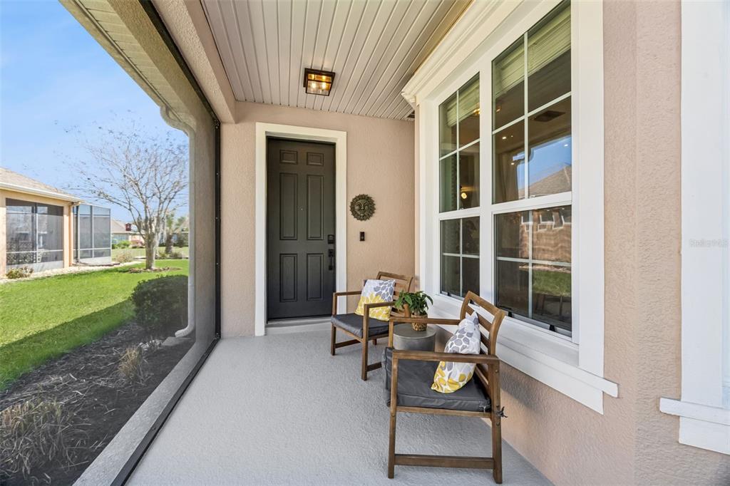 A covered front porch features a dark door, two wooden chairs, and a screened enclosure — 371 SALT MARSH LANE, GROVELAND, FL