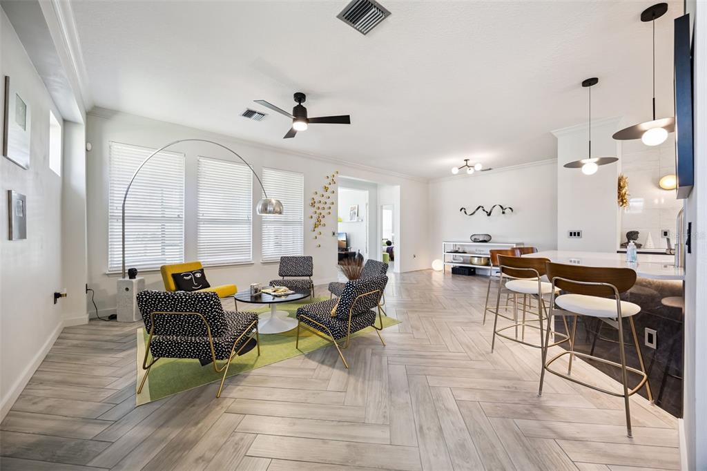 A bright open-concept living room and kitchen featuring herringbone tile flooring and modern furniture — 371 SALT MARSH LANE, GROVELAND, FL