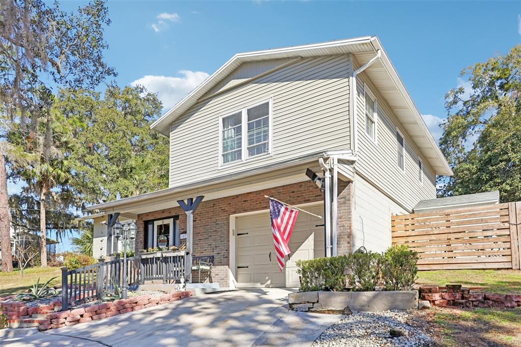 A two-story house with beige siding, a brick facade, and a front-facing garage — 1023 S MORNINGSIDE DRIVE, EUSTIS, FL