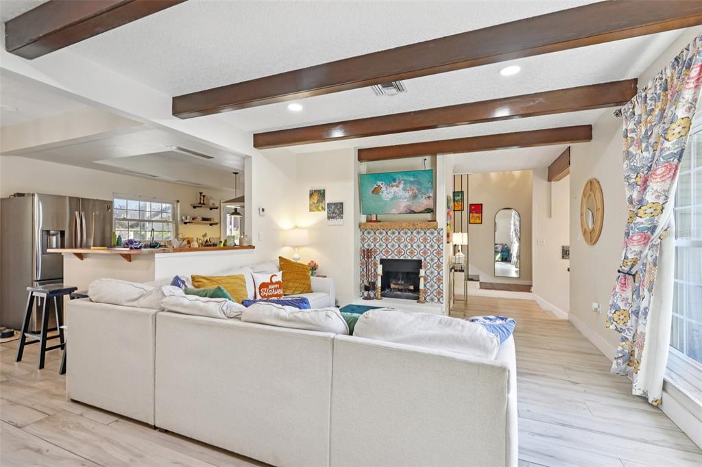 A living room features a large sectional sofa, exposed wood ceiling beams, and light flooring — 1023 S MORNINGSIDE DRIVE, EUSTIS, FL