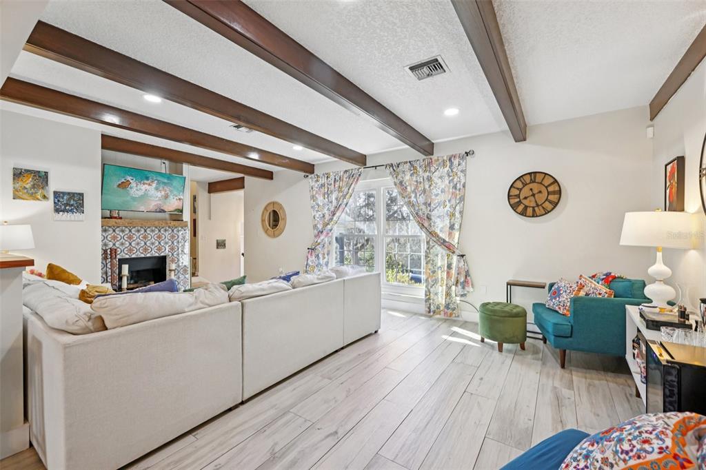 A living room features exposed ceiling beams, a tiled fireplace, and a sectional sofa — 1023 S MORNINGSIDE DRIVE, EUSTIS, FL
