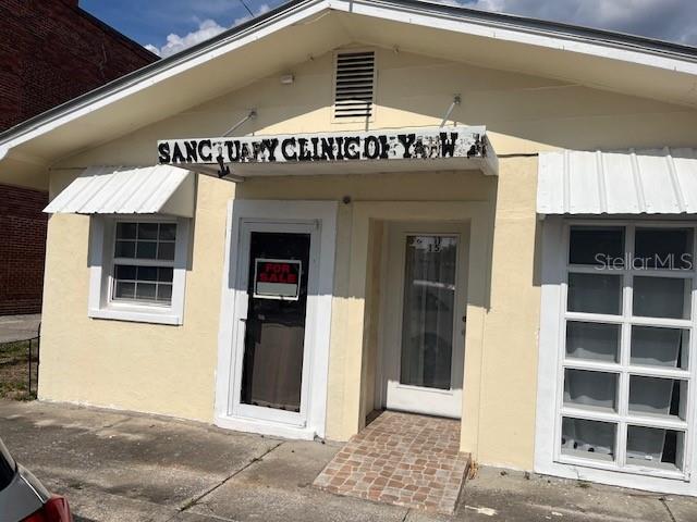 The exterior of a light yellow commercial building features a sign and two entrances — 15 S VERONA AVENUE, AVON PARK, FL