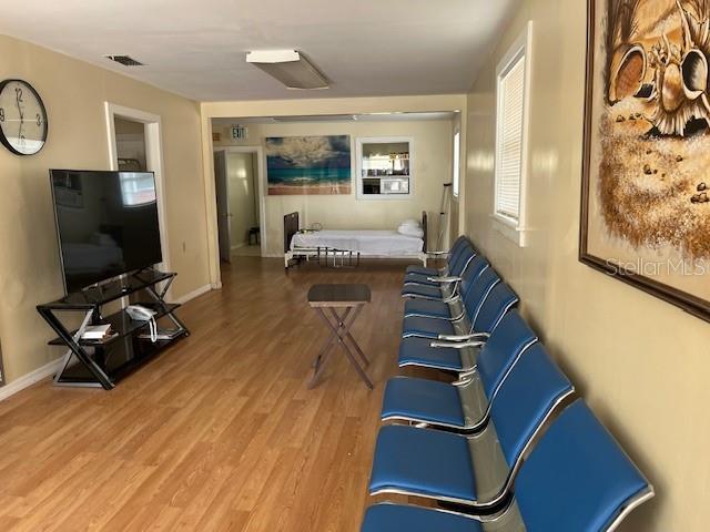 A waiting area with blue chairs, a television on a stand, and a hospital bed — 15 S VERONA AVENUE, AVON PARK, FL