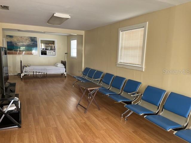 A room with wood-look flooring contains a hospital bed and a row of blue chairs — 15 S VERONA AVENUE, AVON PARK, FL