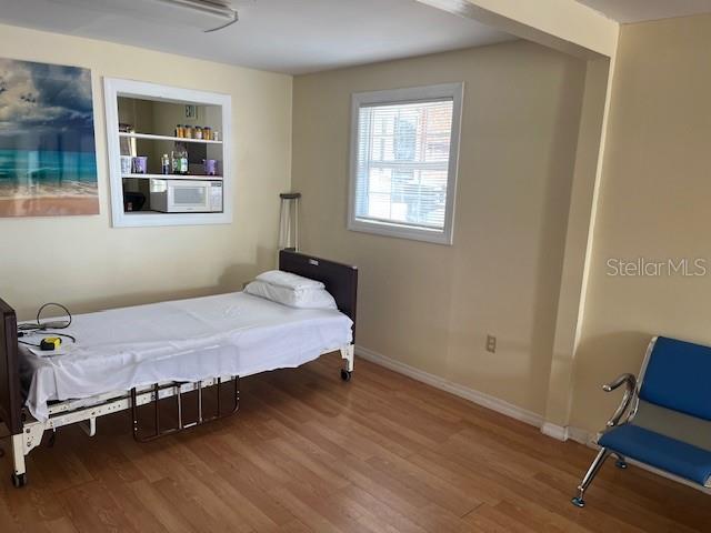A bedroom features a hospital bed, a built-in shelf with a microwave, and a blue chair — 15 S VERONA AVENUE, AVON PARK, FL