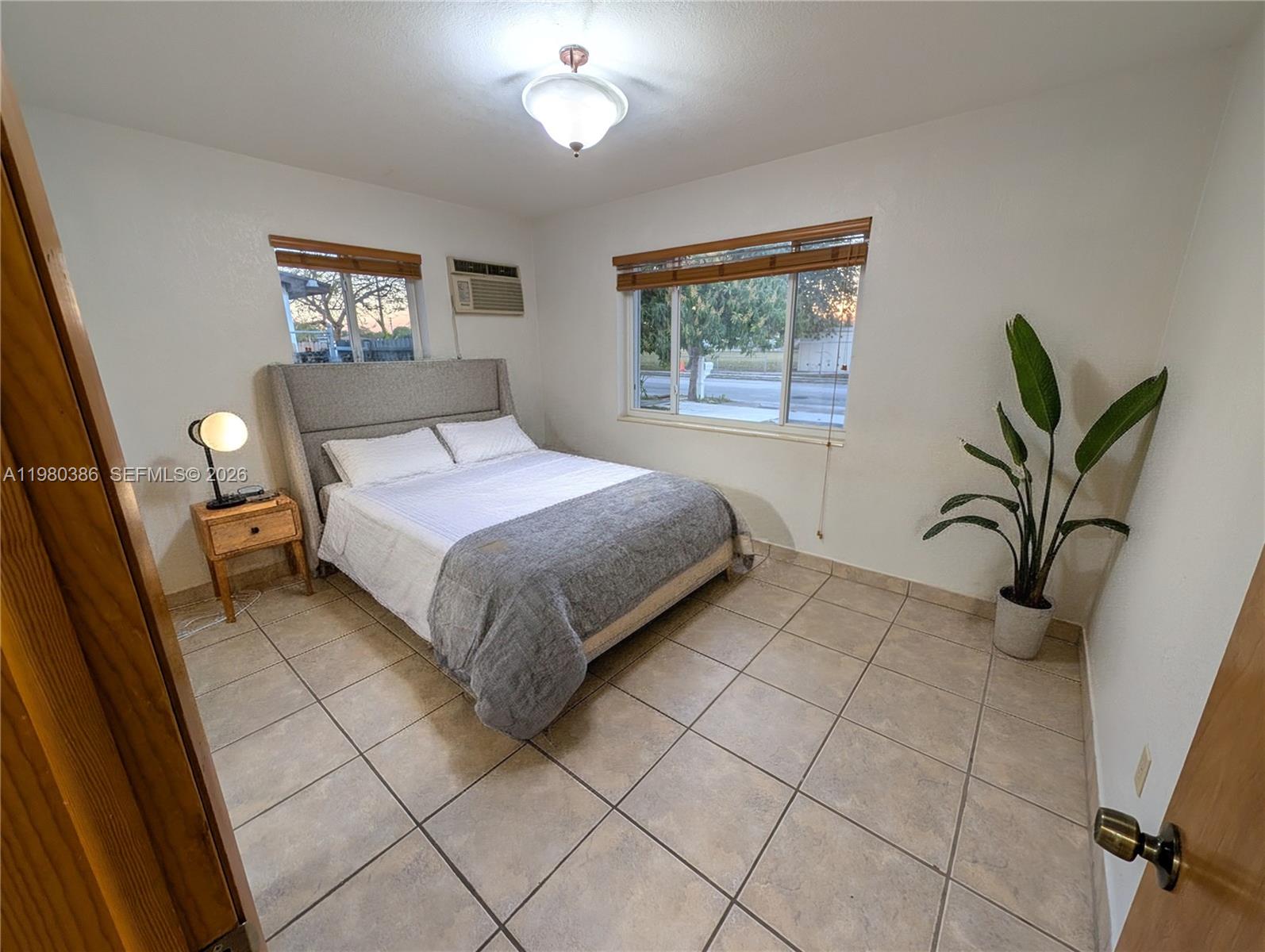 A bedroom features a bed with a gray headboard, tile flooring, and two windows — 1037 SW 76th Ave # 1037, Miami FL 33144, MIAMI, FL