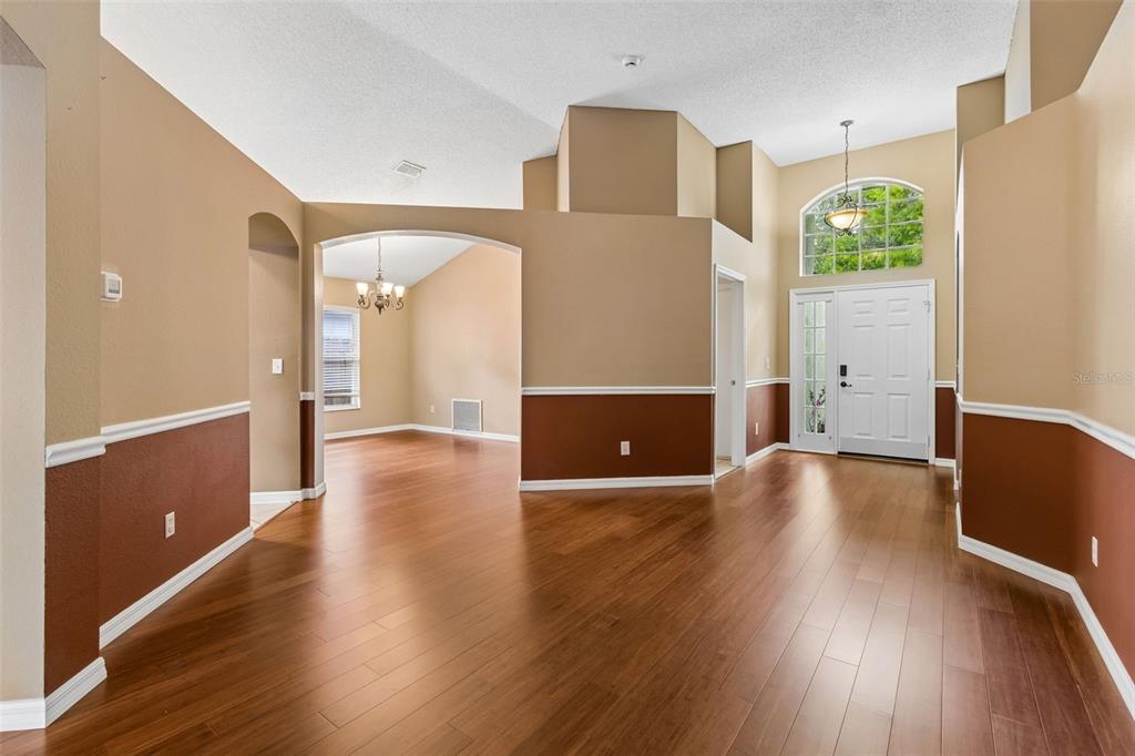 An entryway and dining area feature two-tone walls, wood flooring, and high vaulted ceilings — 5646 PADDOCK TRAIL DRIVE, TAMPA, FL