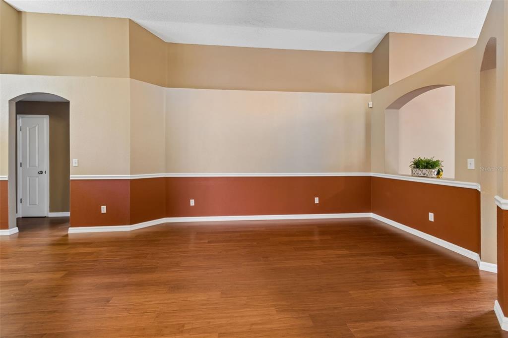 A room with hardwood floors, two-toned walls, a chair rail, and an arched entryway — 5646 PADDOCK TRAIL DRIVE, TAMPA, FL