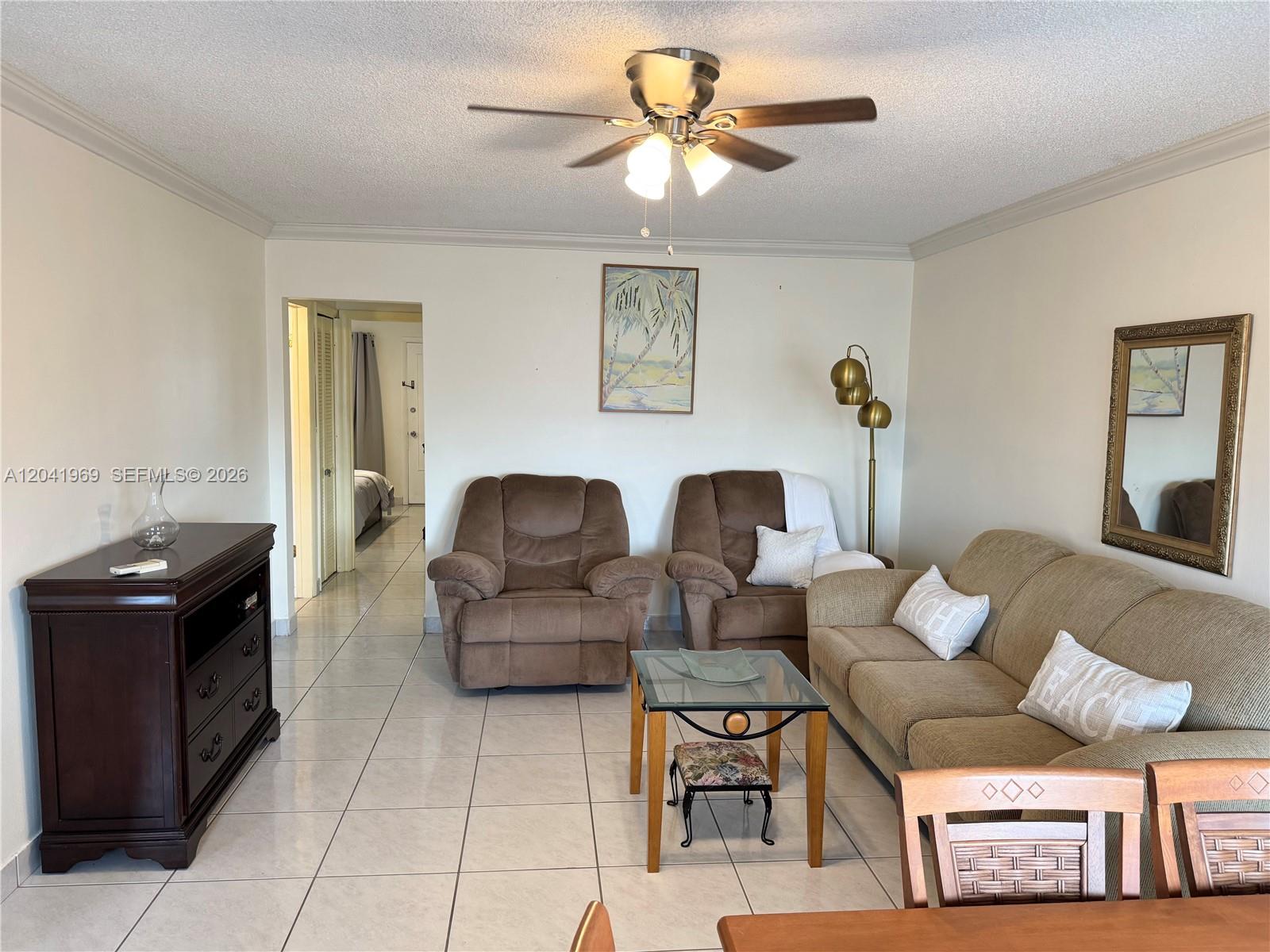 A living room features a brown sofa, two recliners, a glass coffee table, and tile flooring — 920 SW 11th Ave # 11, Hallandale Beach FL 33009, HALLANDALE BEACH, FL