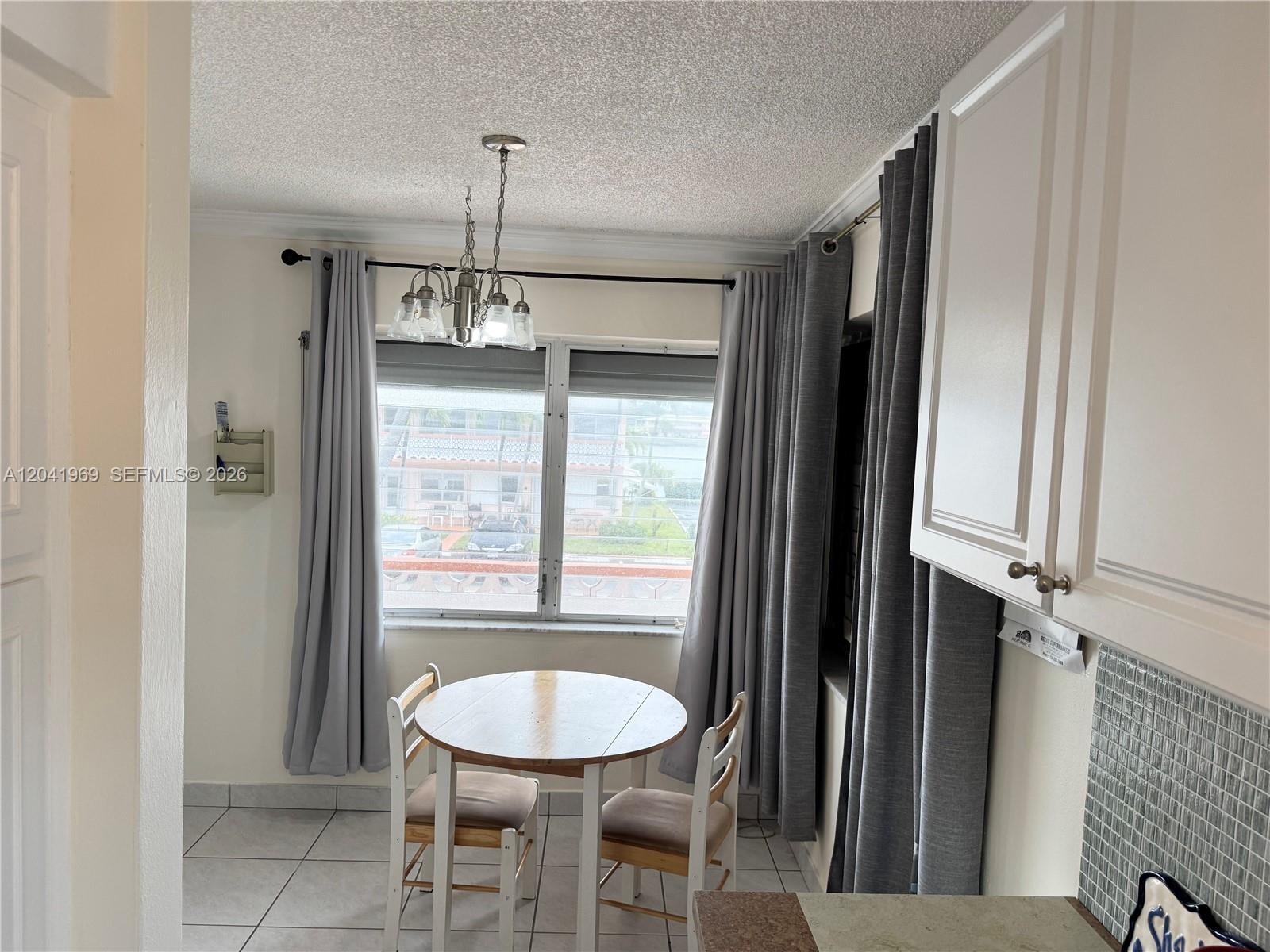 A small dining area features a round wooden table, two chairs, and gray curtains — 920 SW 11th Ave # 11, Hallandale Beach FL 33009, HALLANDALE BEACH, FL