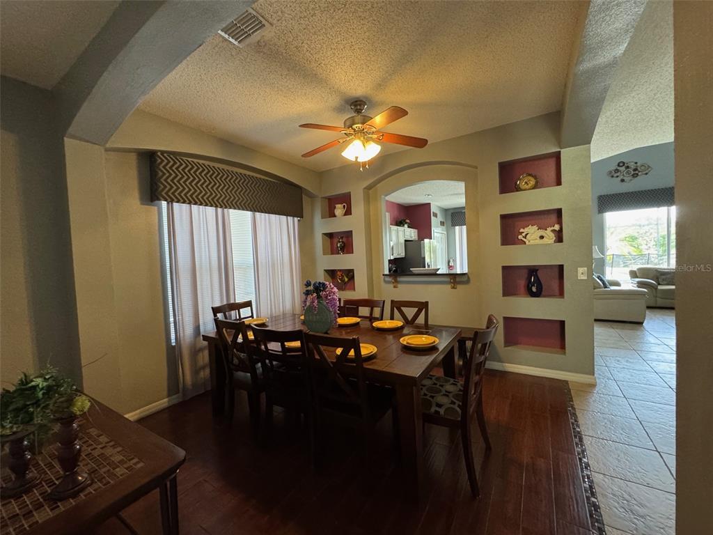 A dining room features a wooden table, chairs, recessed wall niches, and dark wood flooring — 2677 EMERALD ISLAND BOULEVARD, KISSIMMEE, FL