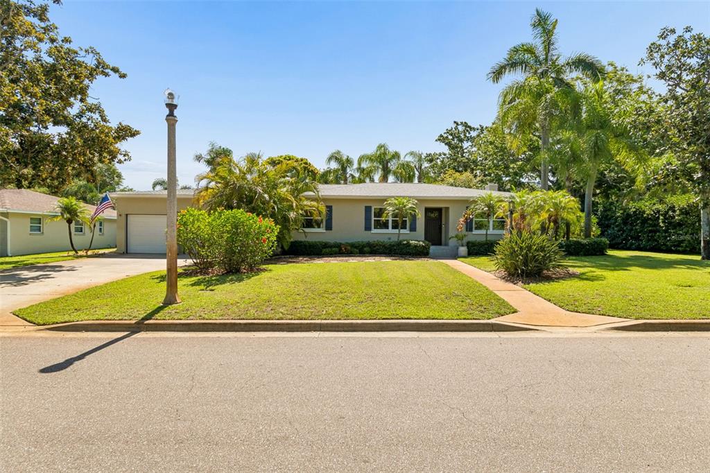 A single-story house with a light-colored exterior, a front lawn, and palm trees — 1743 EAGLES NEST DRIVE, BELLEAIR, FL