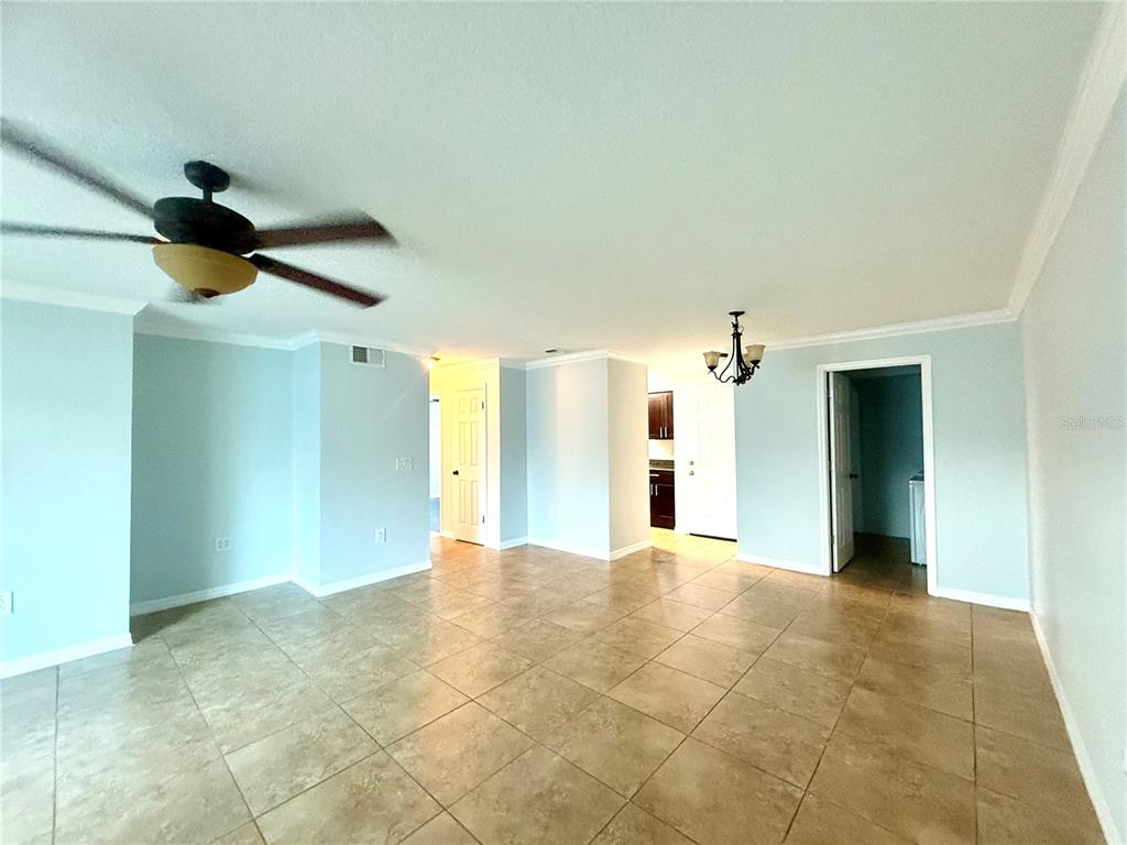 An open-concept living area features light blue walls, tan tile flooring, and a ceiling fan — 209 DORCHESTER SQUARE UNIT 209, LAKE MARY, FL